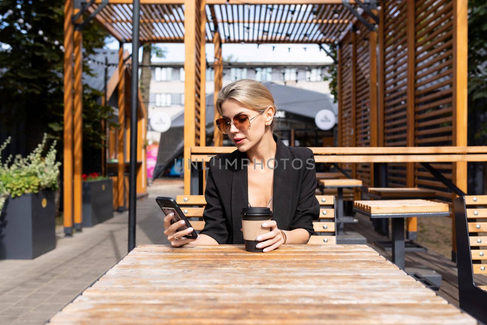 middle-aged woman in a cafe drinks coffee and looks at the phone.
