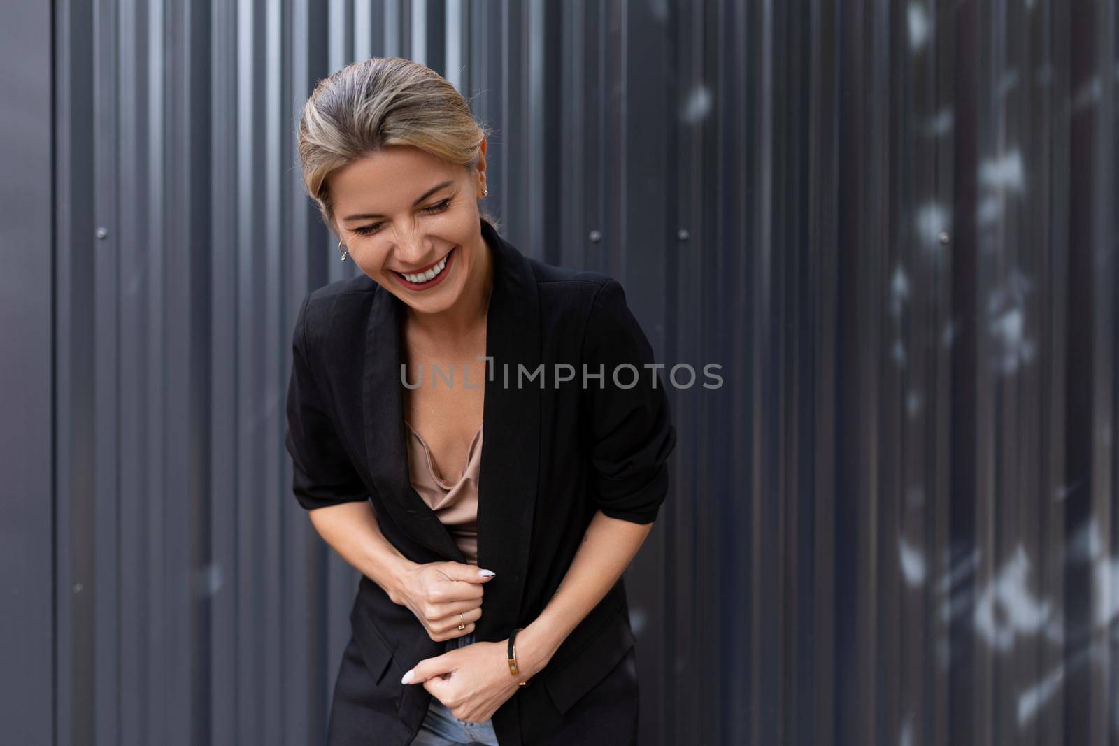 middle-aged businesswoman laughs bending against the background of a gray wall in the office.