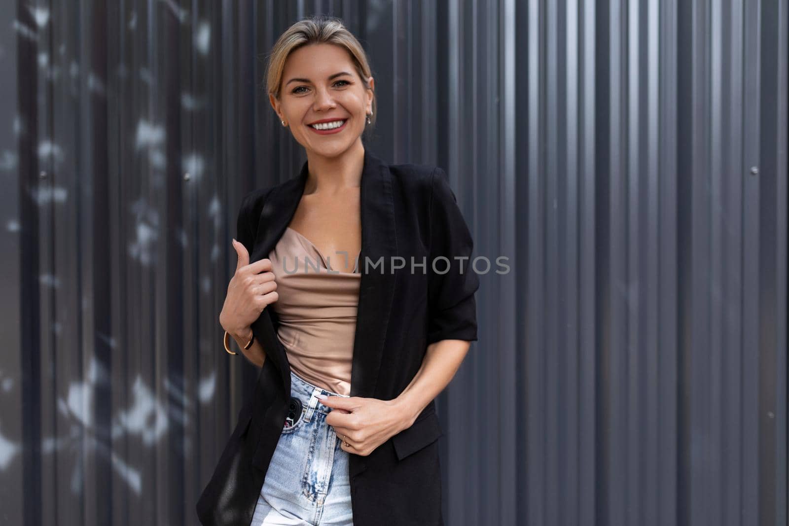 portrait of a successful business woman with a wide smile with teeth against a gray wall.