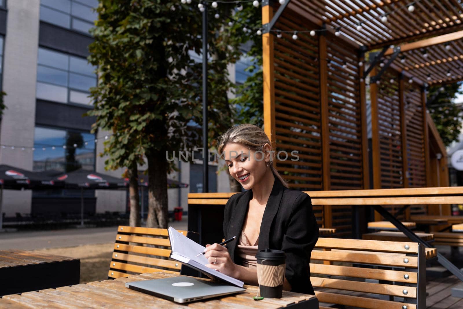 portrait of successful woman working outdoors with laptop diary.