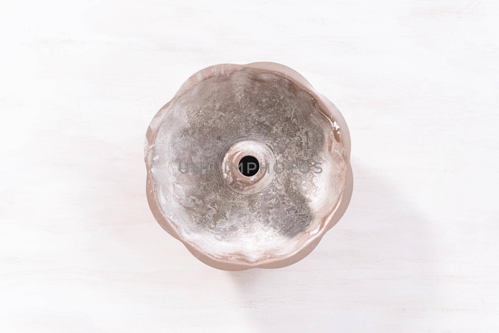 Flat lay. Greased metal bundt cake pan to bake chocolate bundt cake with chocolate frosting.
