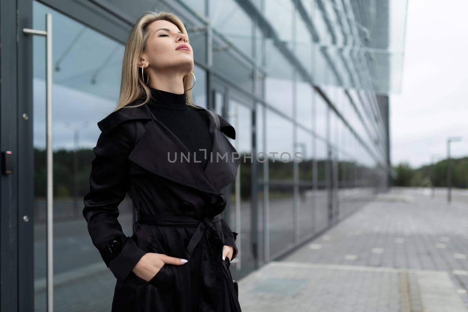 portrait of a middle-aged businesswoman woman in a strict black business style against the background of a glass facade of a business center.