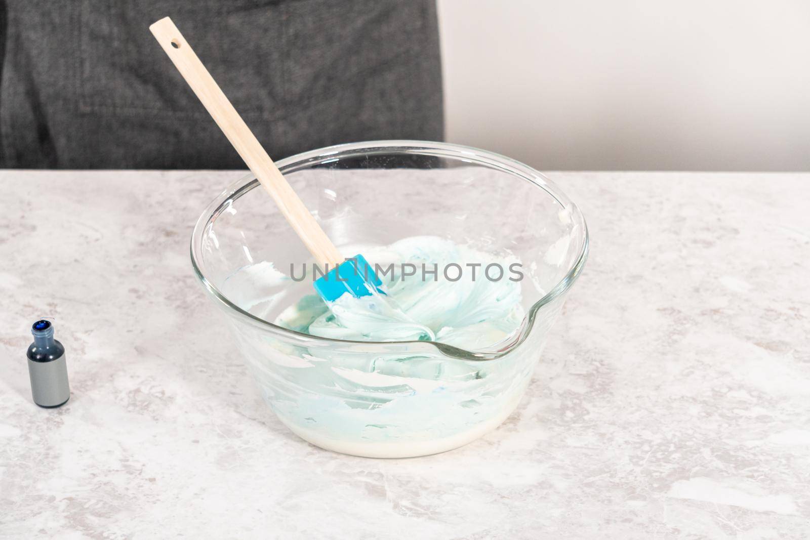 Mixing in blue food coloring into the buttercream frosting.