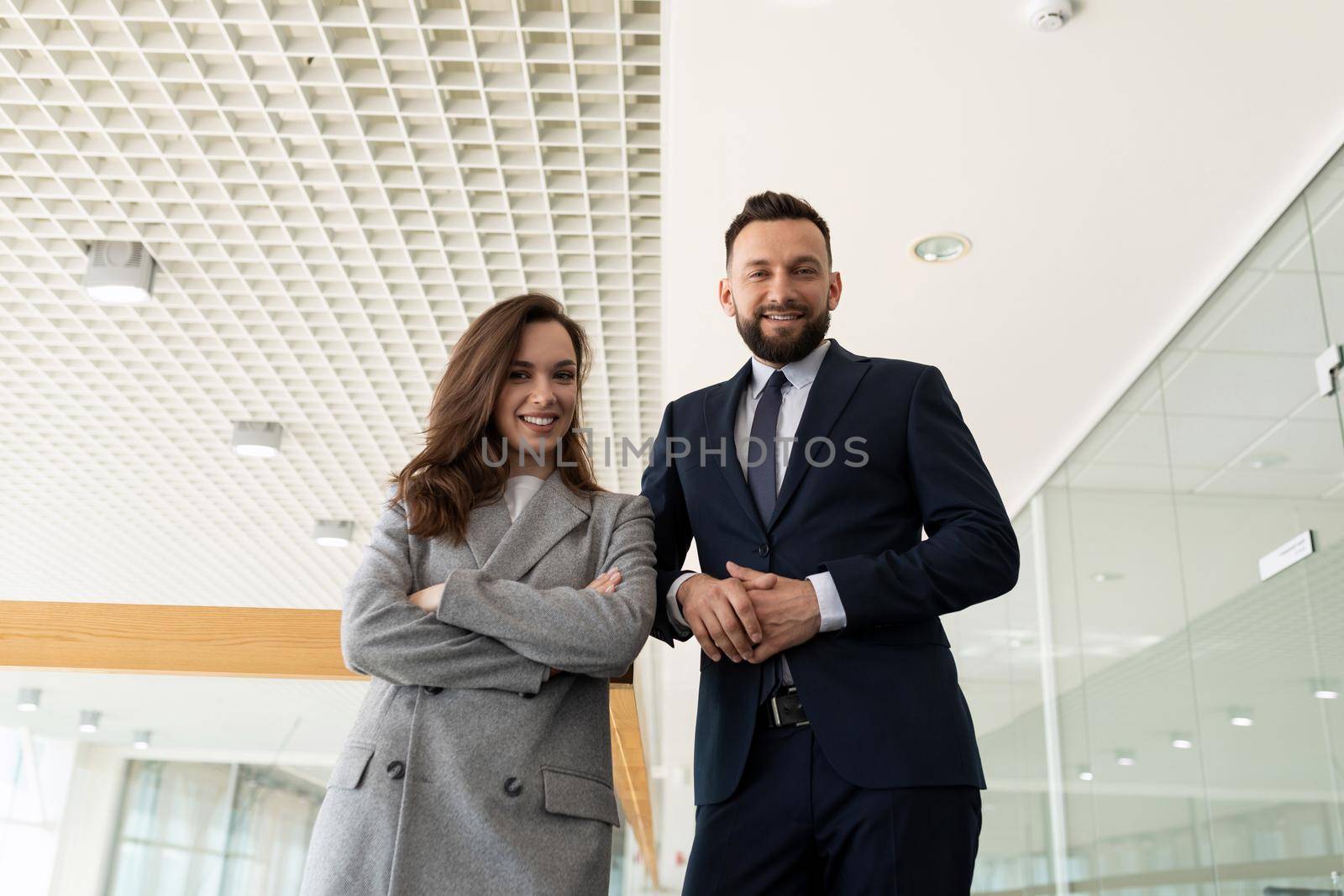 two presentable lawyers against the backdrop of a large office.