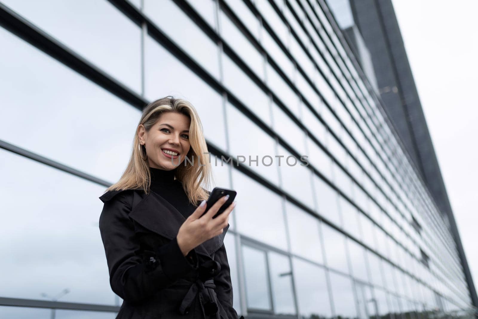 young woman Businessman with a phone next to the glass facade of an office building.