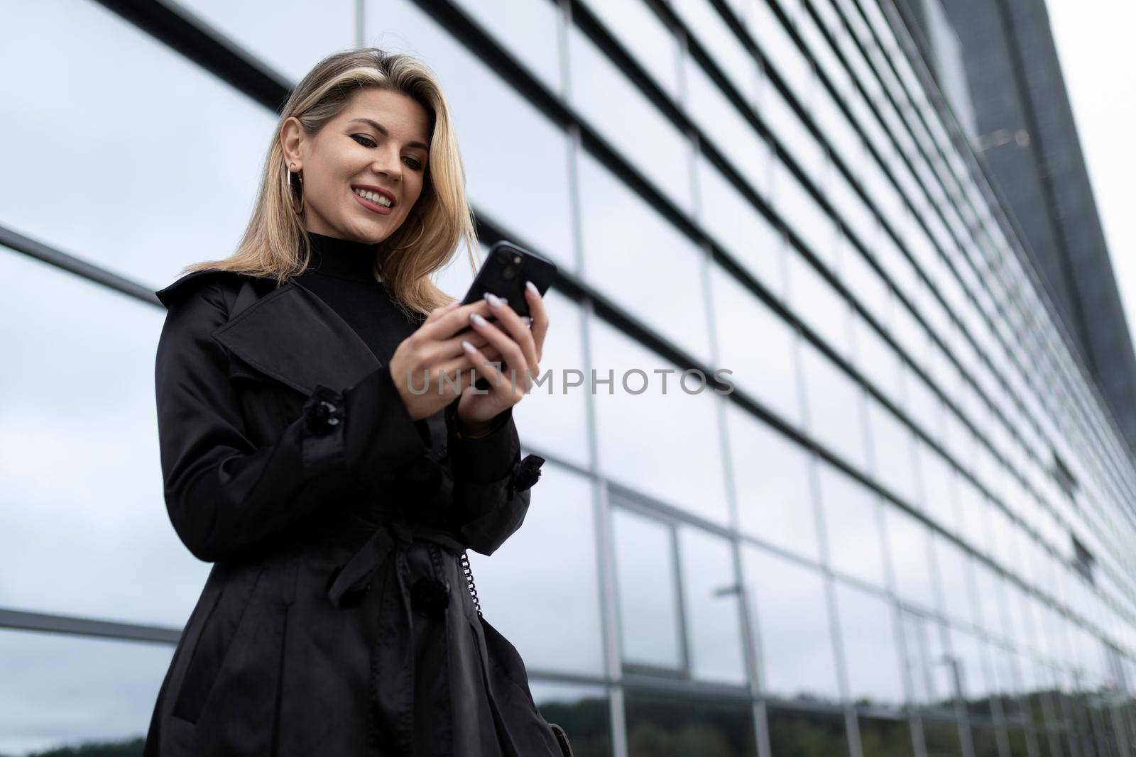 Middle-aged business woman with a mobile phone against the backdrop of an office building.