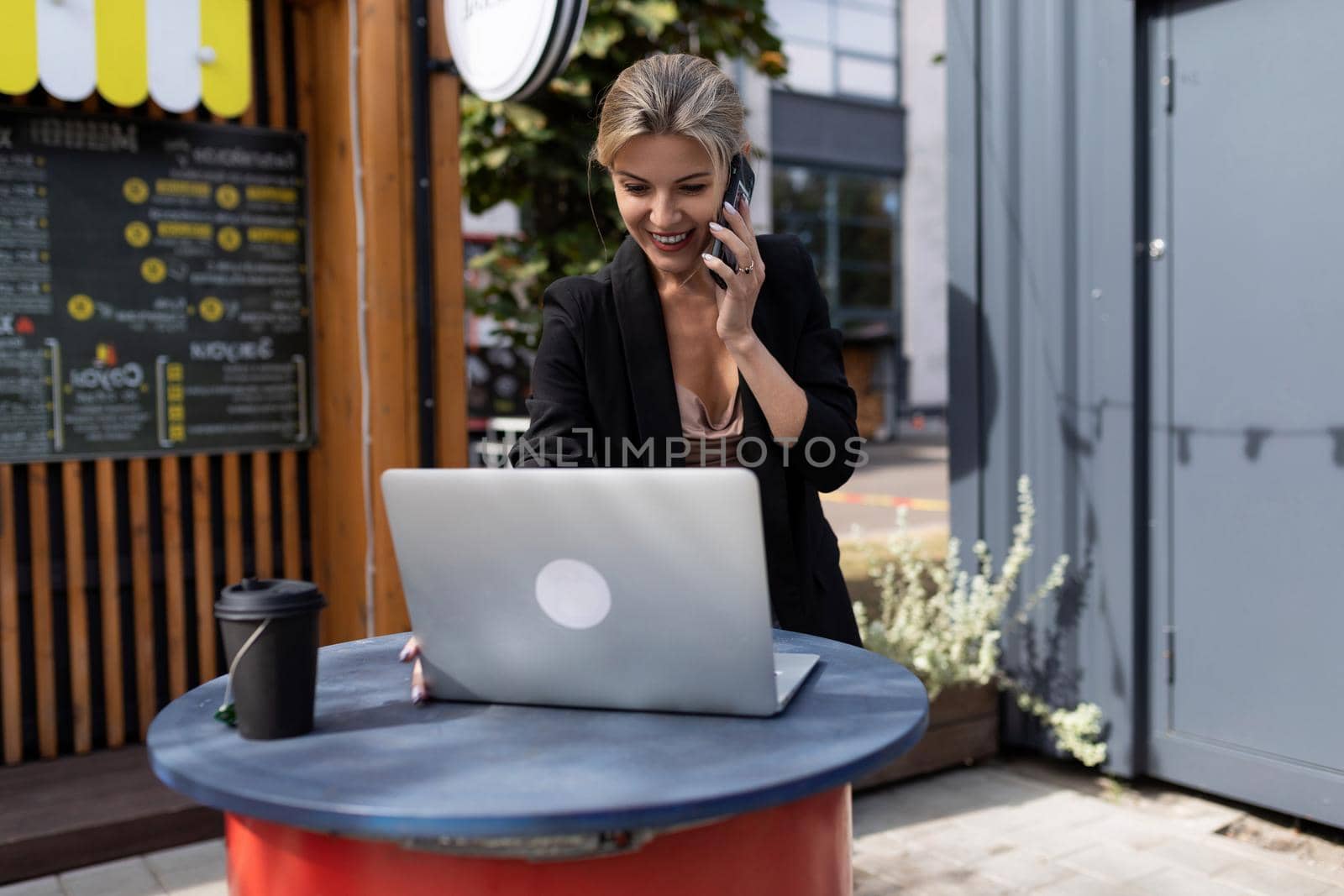 young successful woman working at a laptop at a table in a street cafe.
