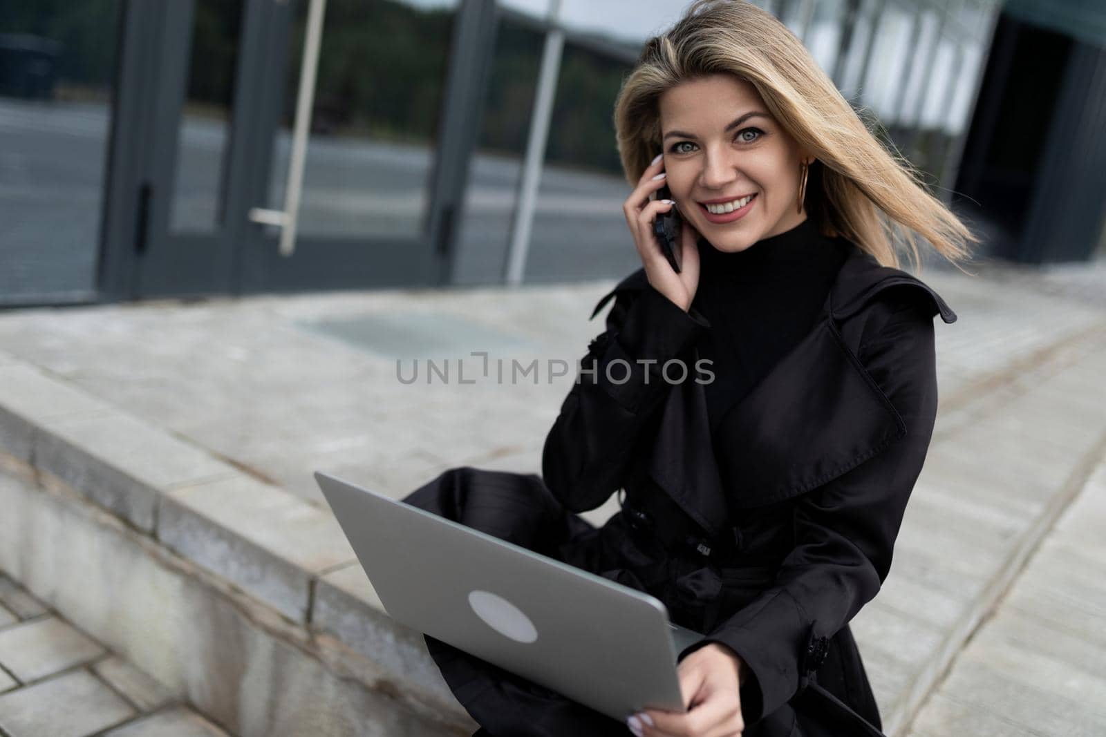 modern woman head successful businessman working online with a laptop on the background of an office building.