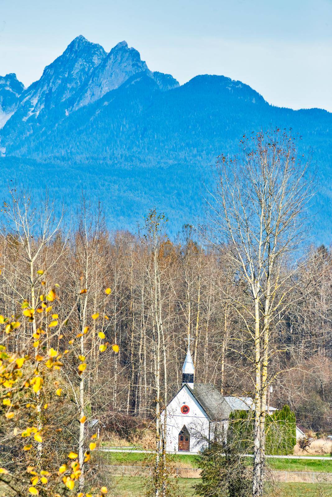Small white church on autumn season in sunlight.