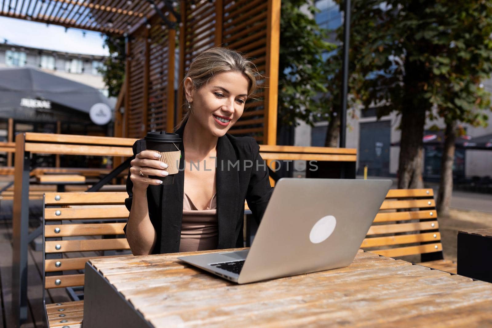 strong businessman drinking coffee i working on laptop outdoors.