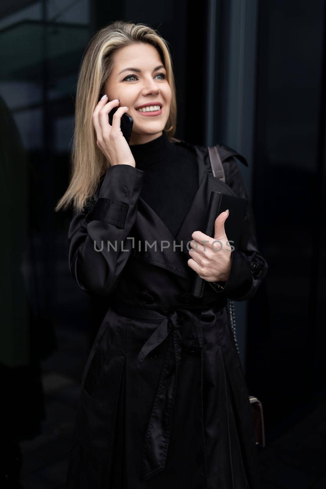 portrait of a business woman on the background of a black glass building with a smile looking into the distance.