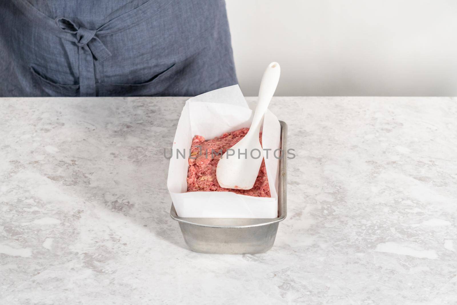 Preparing classic meatloaf in a loaf pan lined with parchment paper.