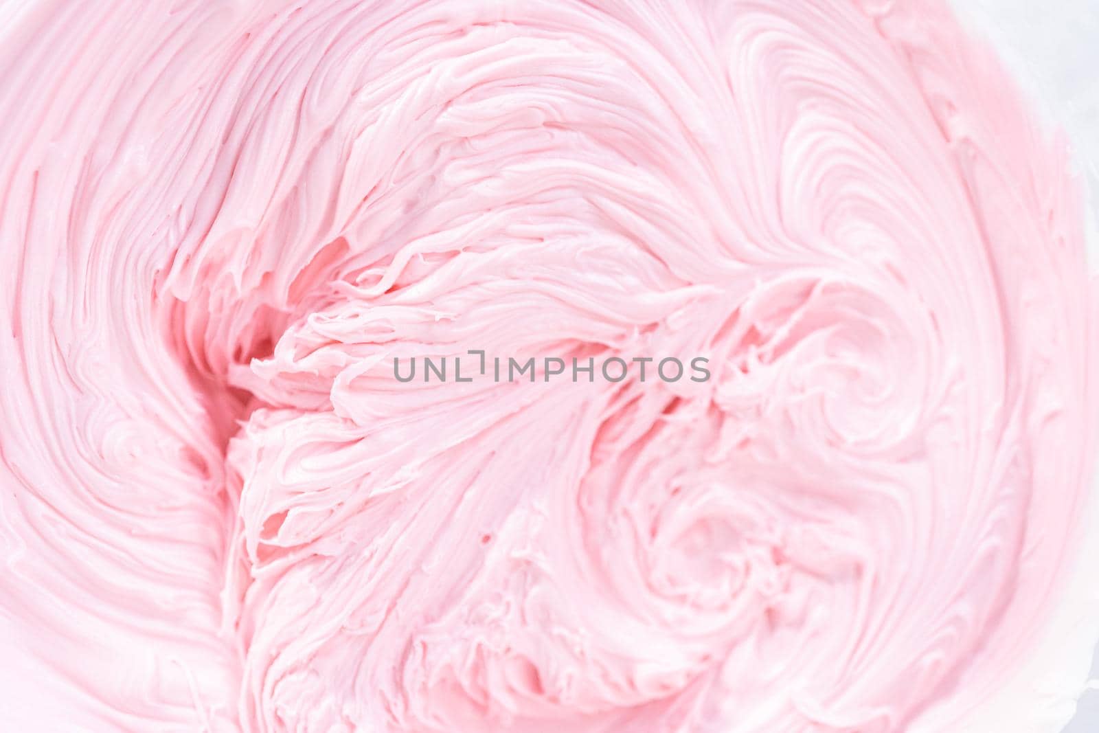 Close up view. Mixing in pink food coloring into a vanilla buttercream frosting for decorating funfettti bundt cake.