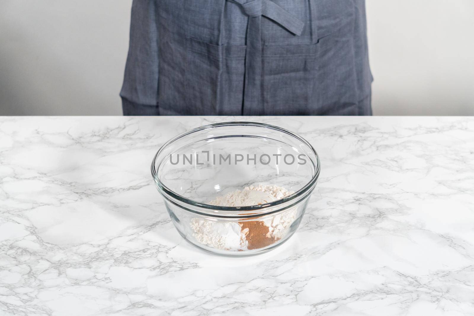 Mixing dry ingredients in a large glass mixing bowl to bake soft oatmeal raisin walnut cookies.