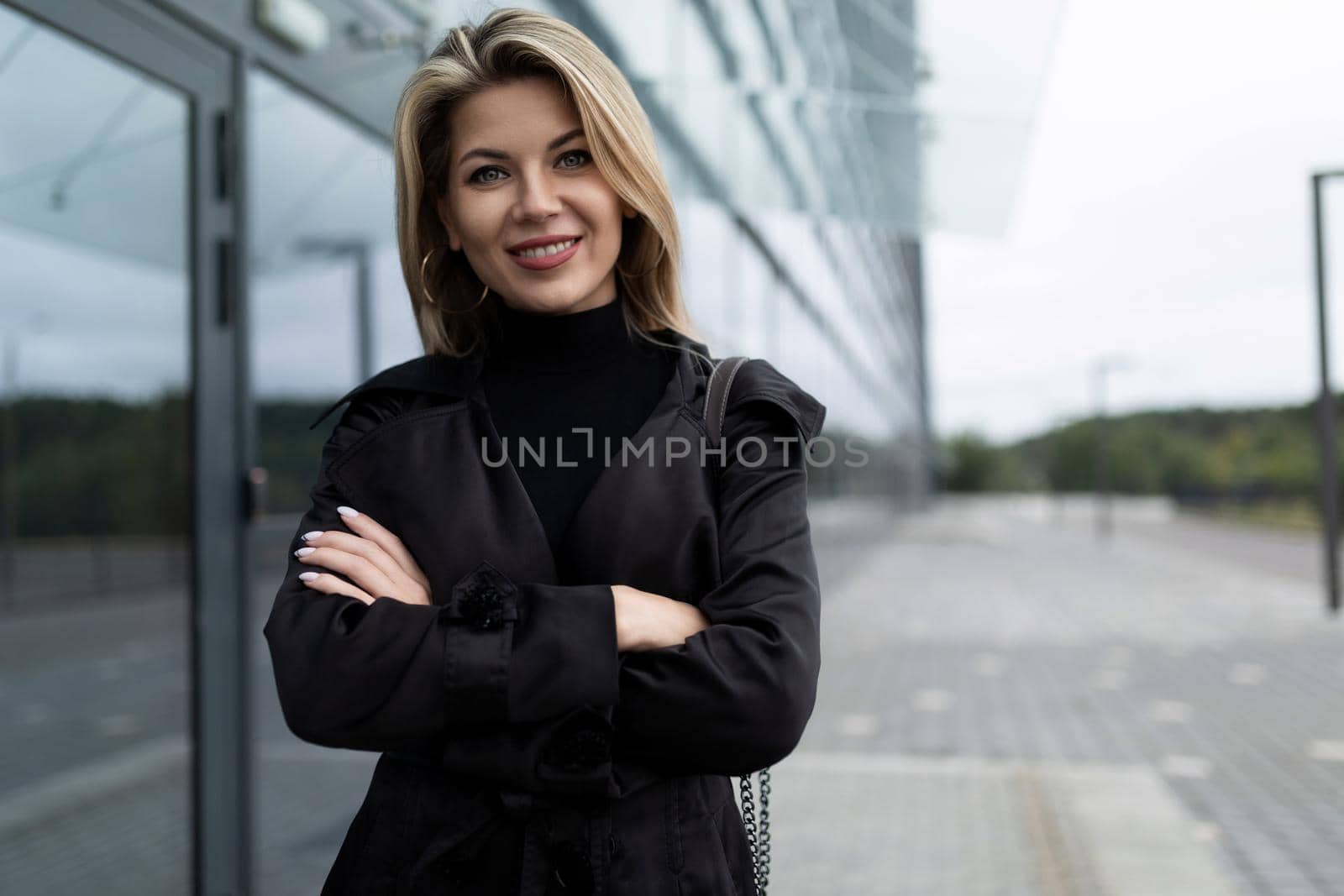 portrait of a successful business woman in a black business suit next to the entrance to the office building.