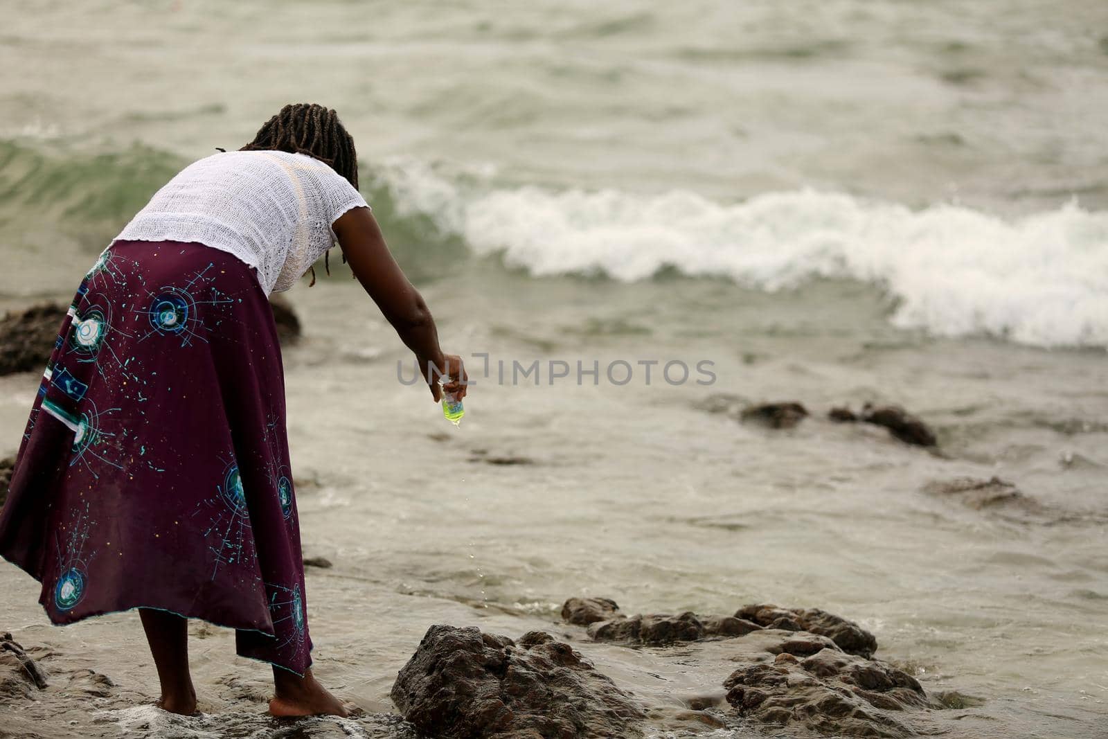salvador, bahia / brazil - february 2, 2020: devotee of yemanja, candomble entity is seen offering perfume to the orixa on the Rio Vermelho beach in the city of Salvador during religious celebration.