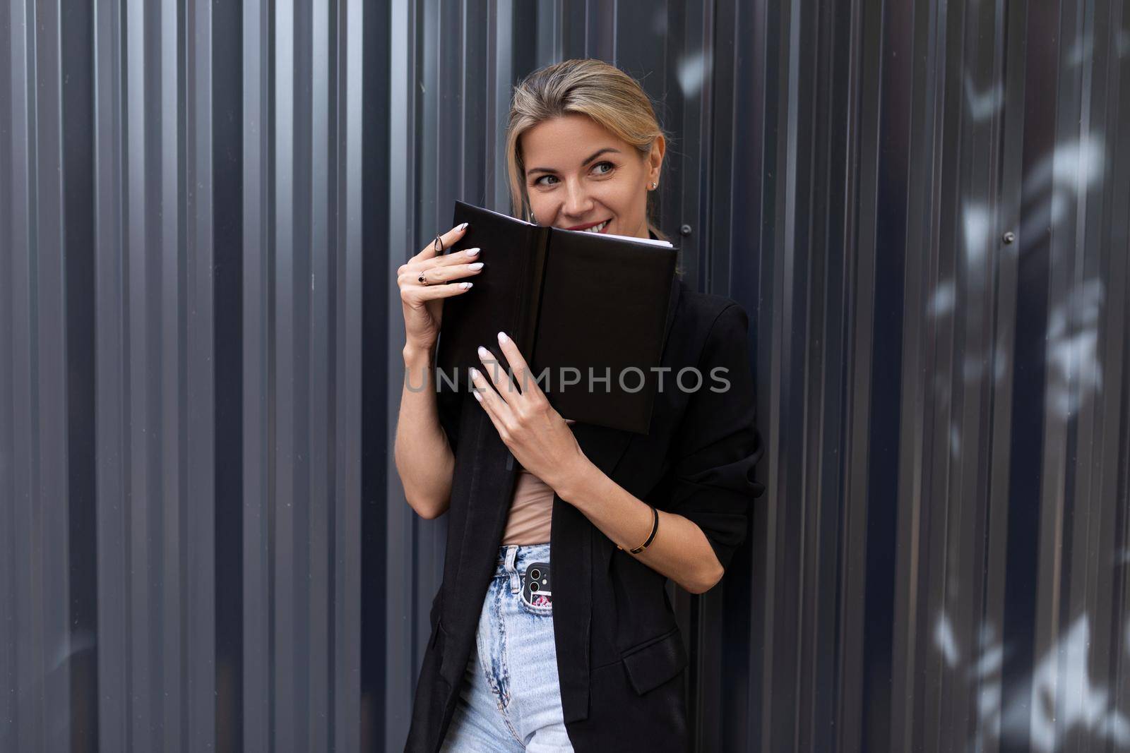office worker middle-aged woman with a smile holding a notebook in her hands looking at the camera.