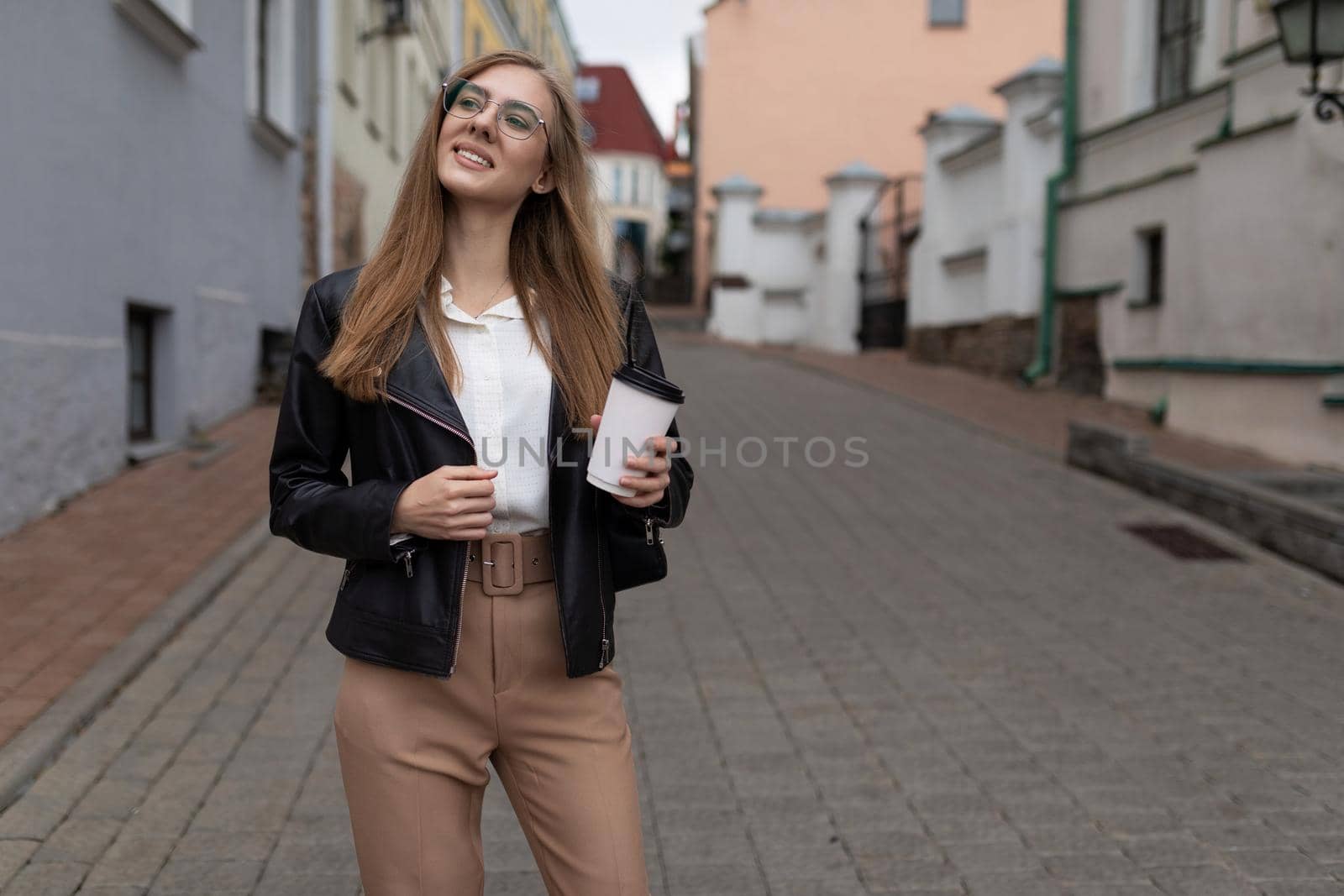 young woman Tourist walks around the city with a cup of coffee in her hands and a phone.