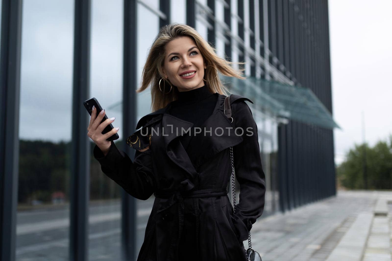 a successful middle-aged businessman hurries to work with a mobile phone against the backdrop of an office building.