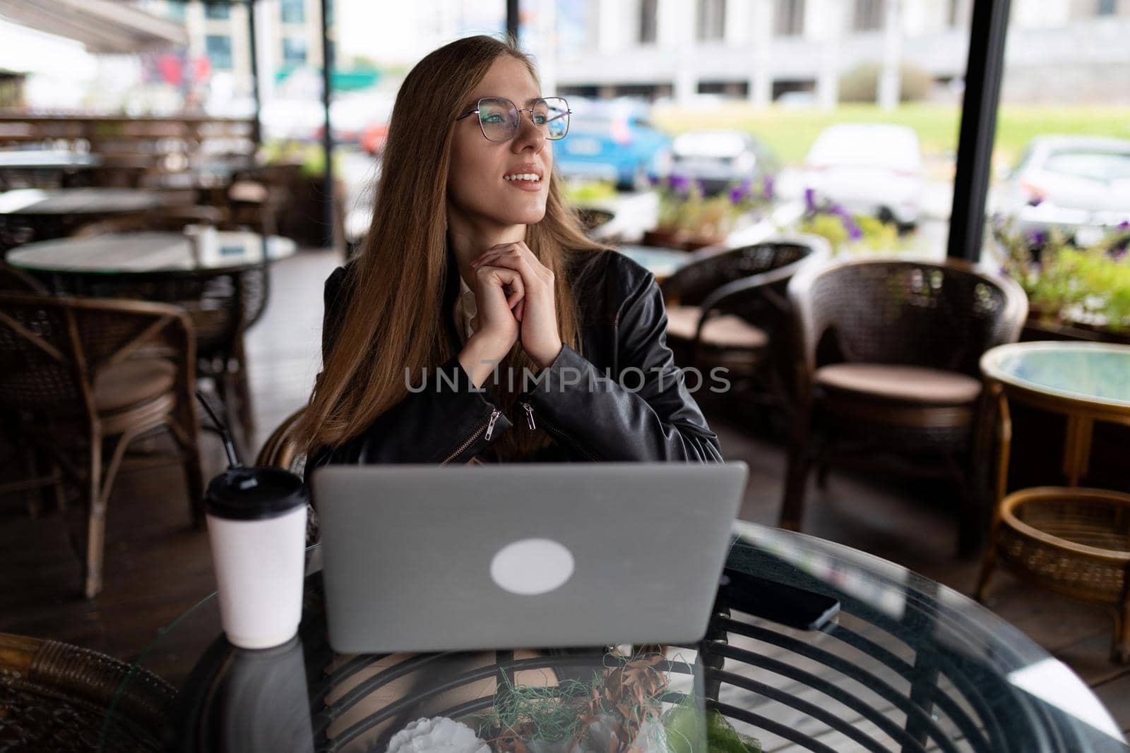 young female freelancer working on a laptop in a city cafe.