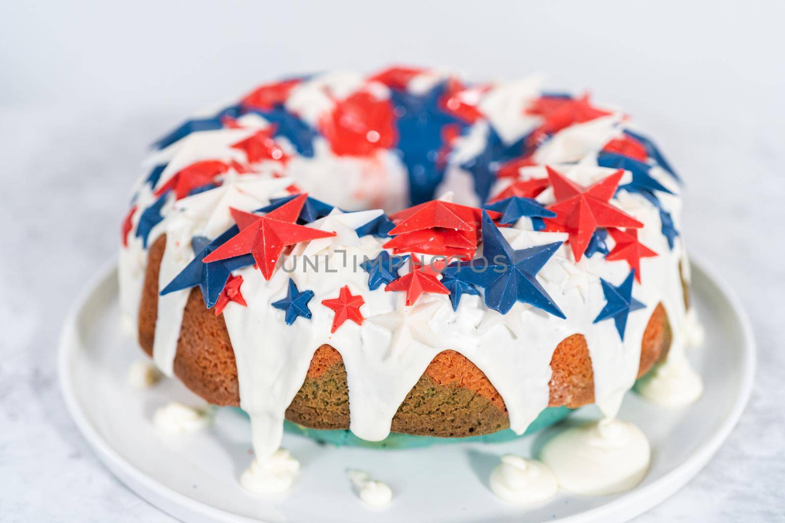 July 4th bundt cake covered with a vanilla glaze and decorated with chocolate stars on a white plate.