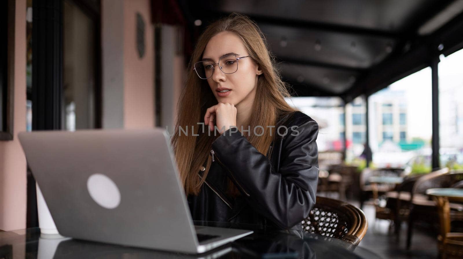 young woman working online on laptop in city cafe.