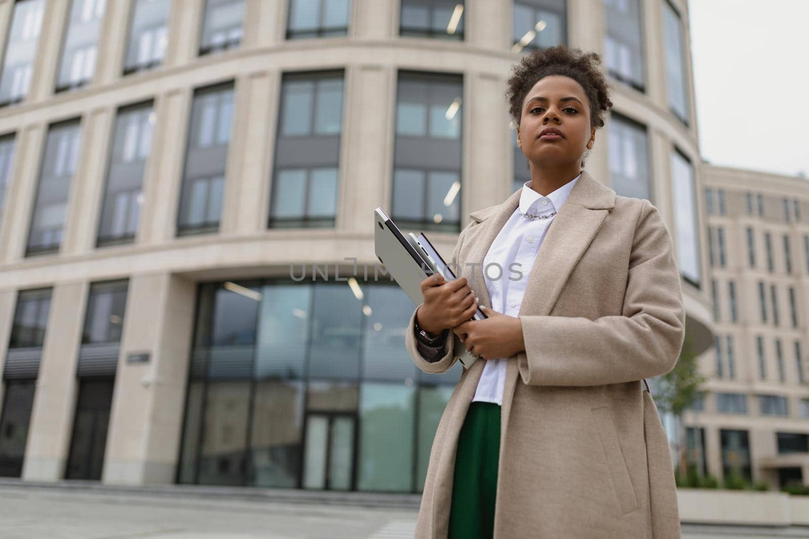 african american woman entrepreneur in business clothes with a laptop in her hands against the backdrop of a business center.
