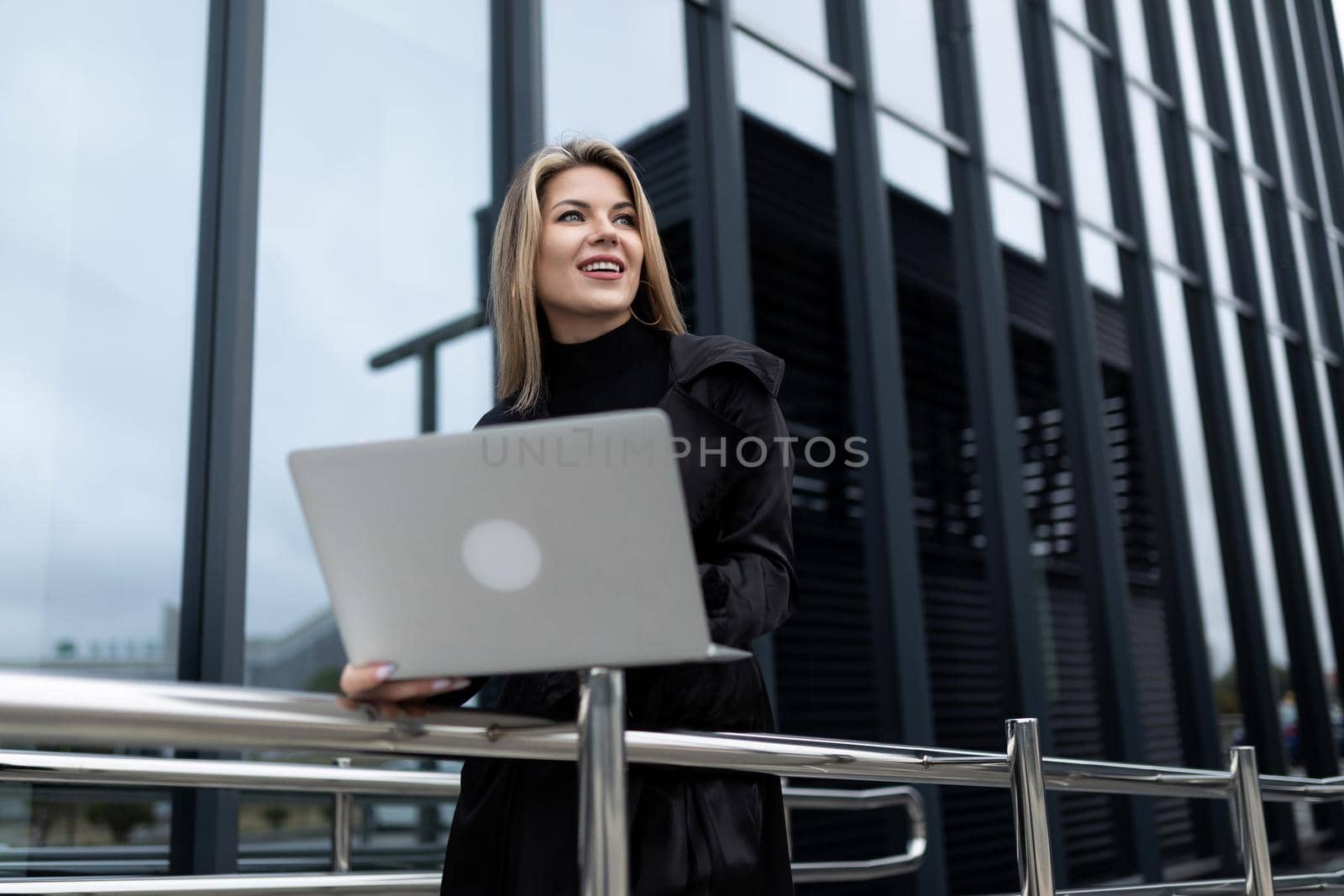 woman businessman head working on a laptop online against the backdrop of an office building.