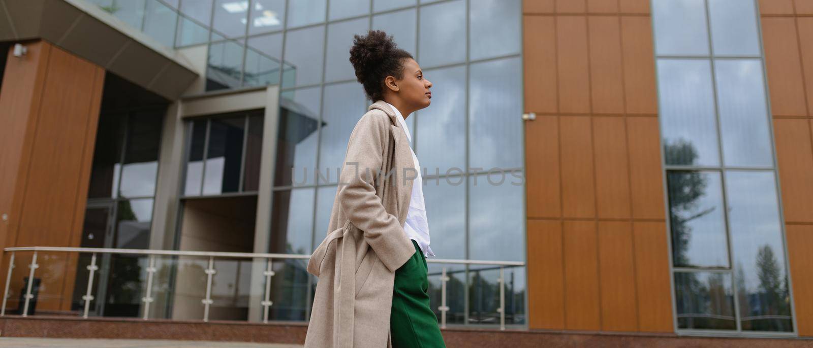young African American woman walking in front of the administrative building by TRMK