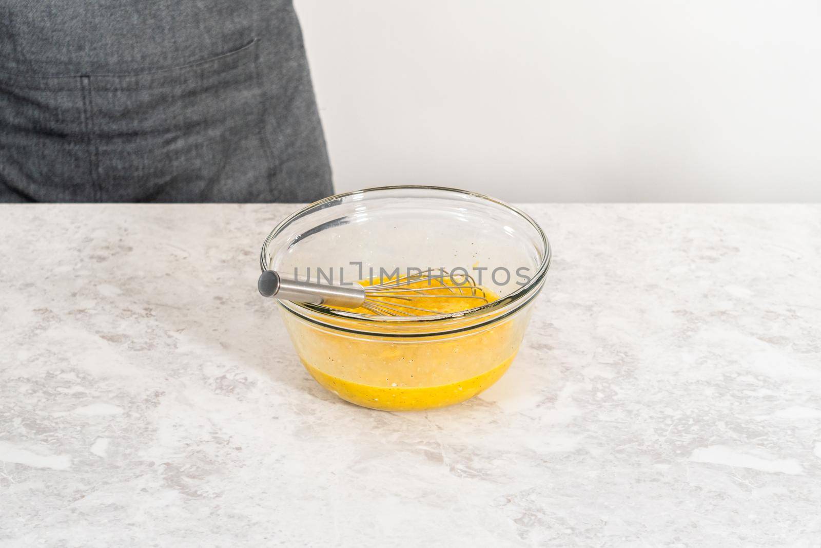 Mixing ingredients with a hand whisk in a glass mixing bowl to make egg bites.