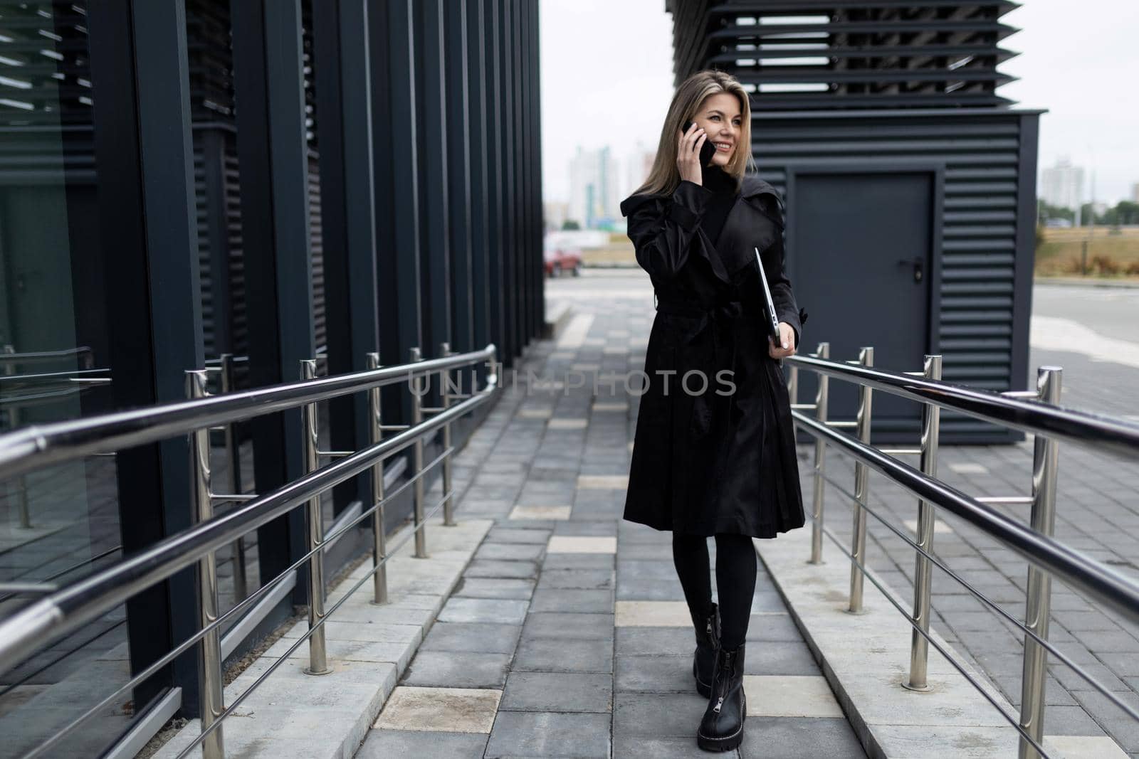a middle-aged business woman walks into an office building talking on the phone.