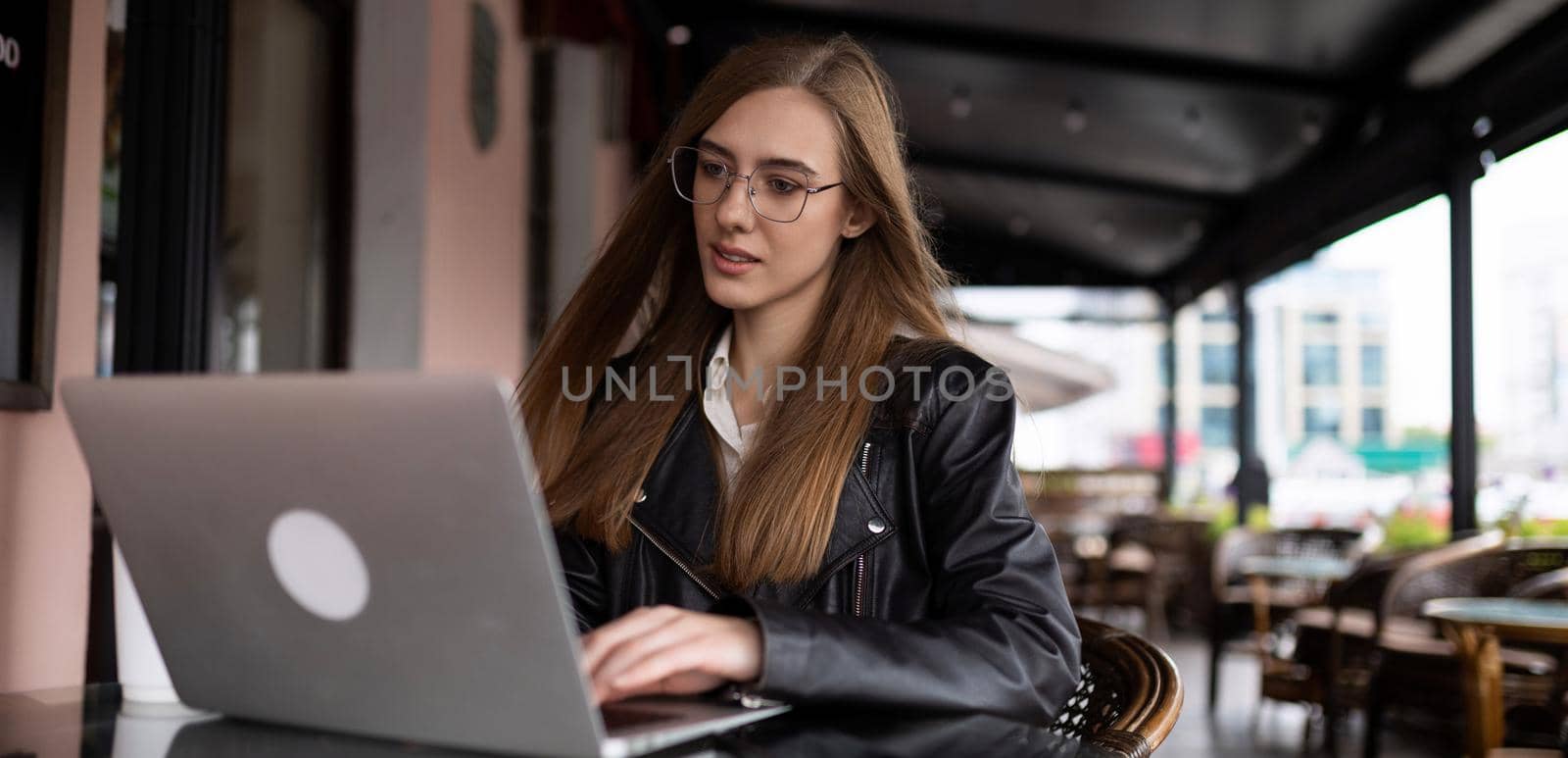 woman freelancer working online on laptop in city cafe.