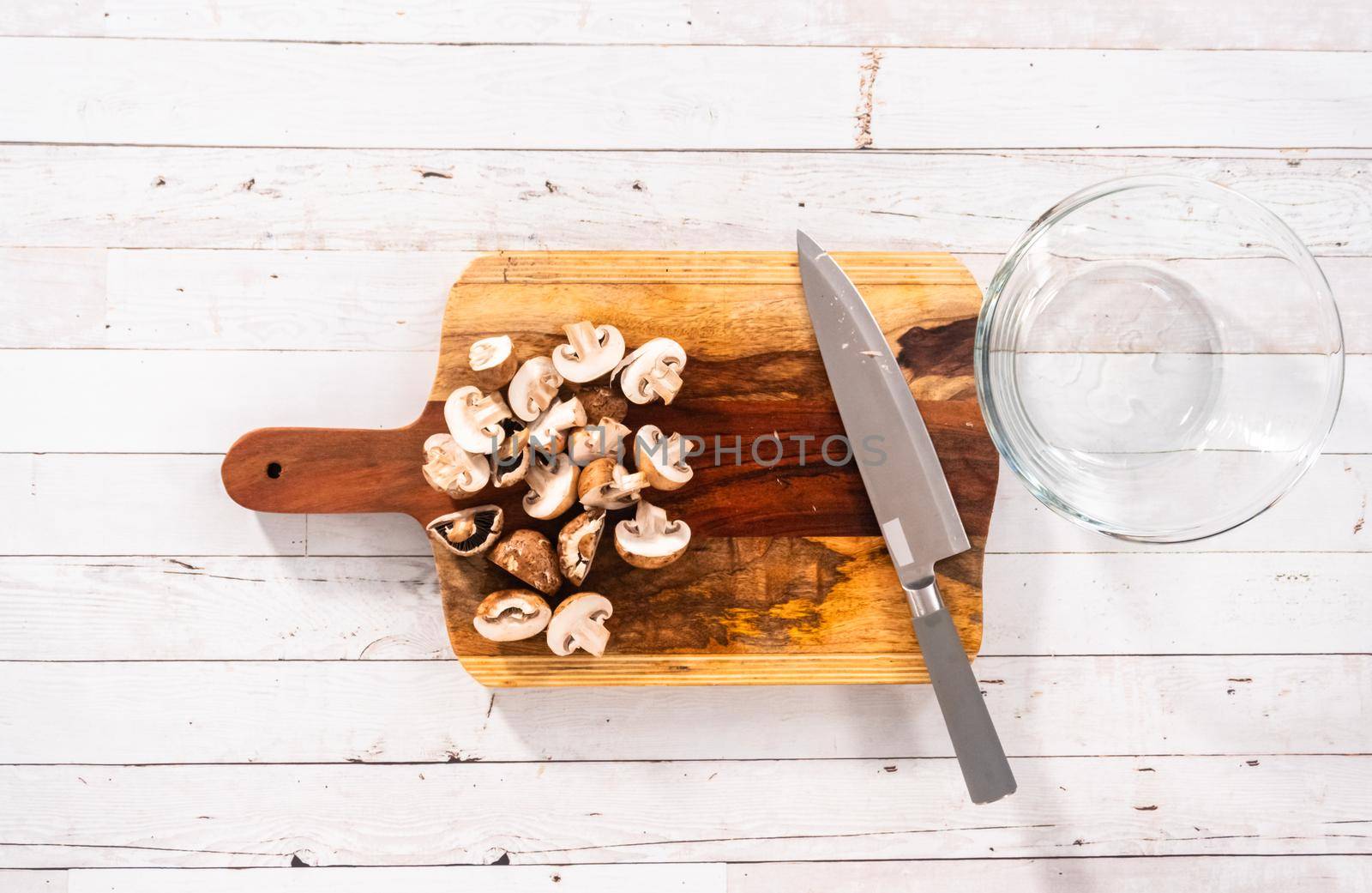 Flat lay. Cutting organic bella mushrooms on a wood cutting board.