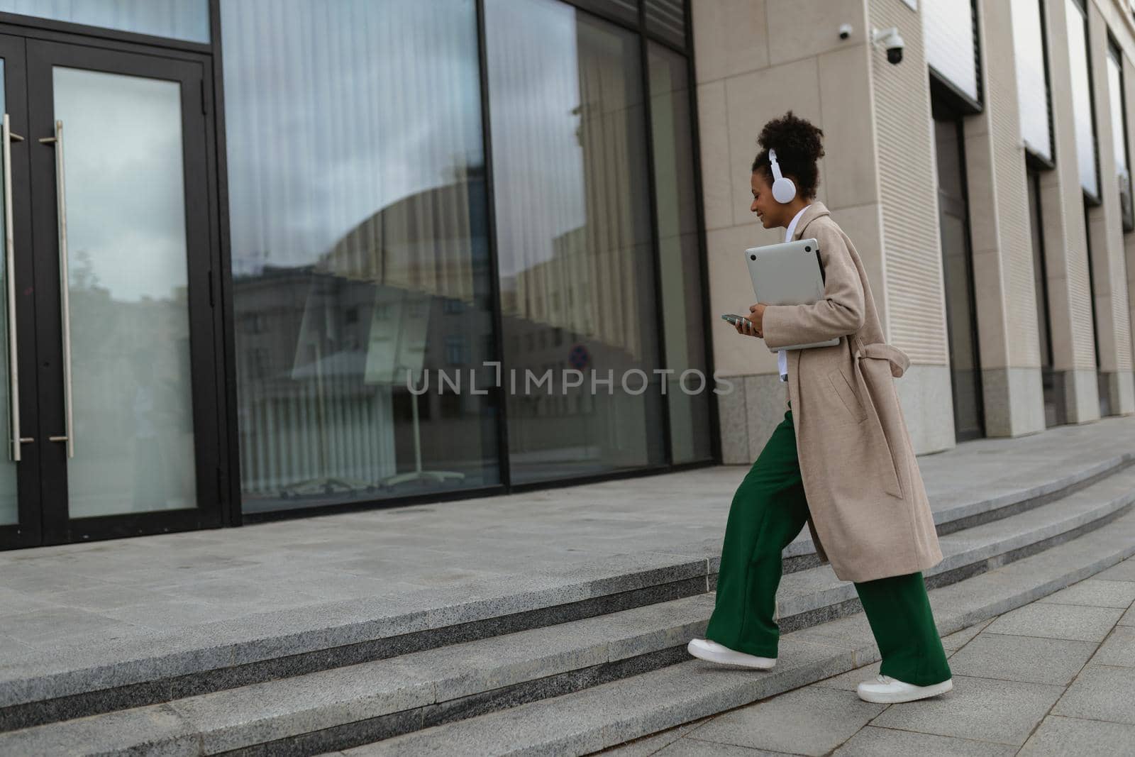 young american woman with laptop and headphones enters the business center.