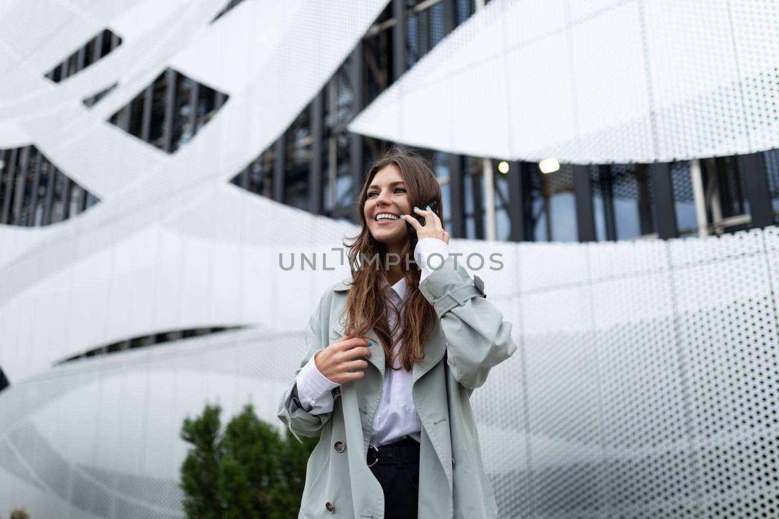 young beautiful woman talking on a mobile phone in stylish clothes on the background of a modern building.