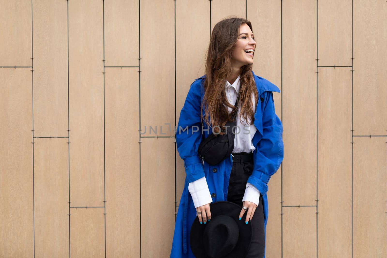 young cheerful female student against a beige wall.