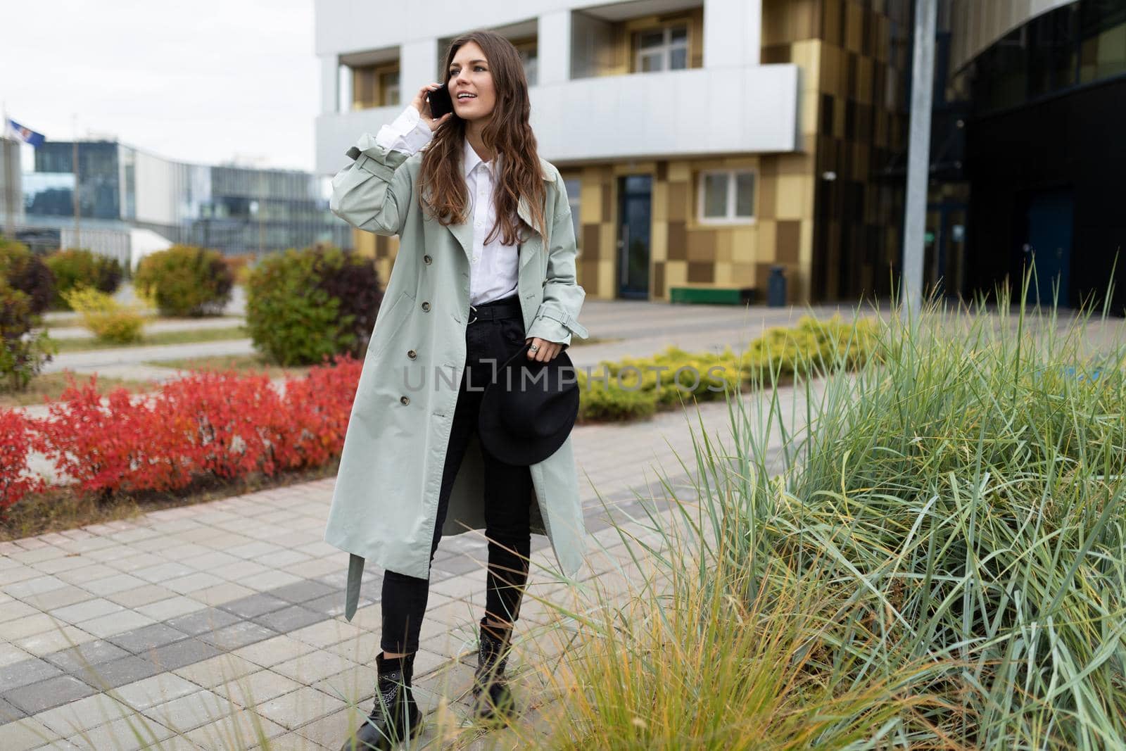 stylish young woman talking on a mobile phone on the background of modern city buildings.
