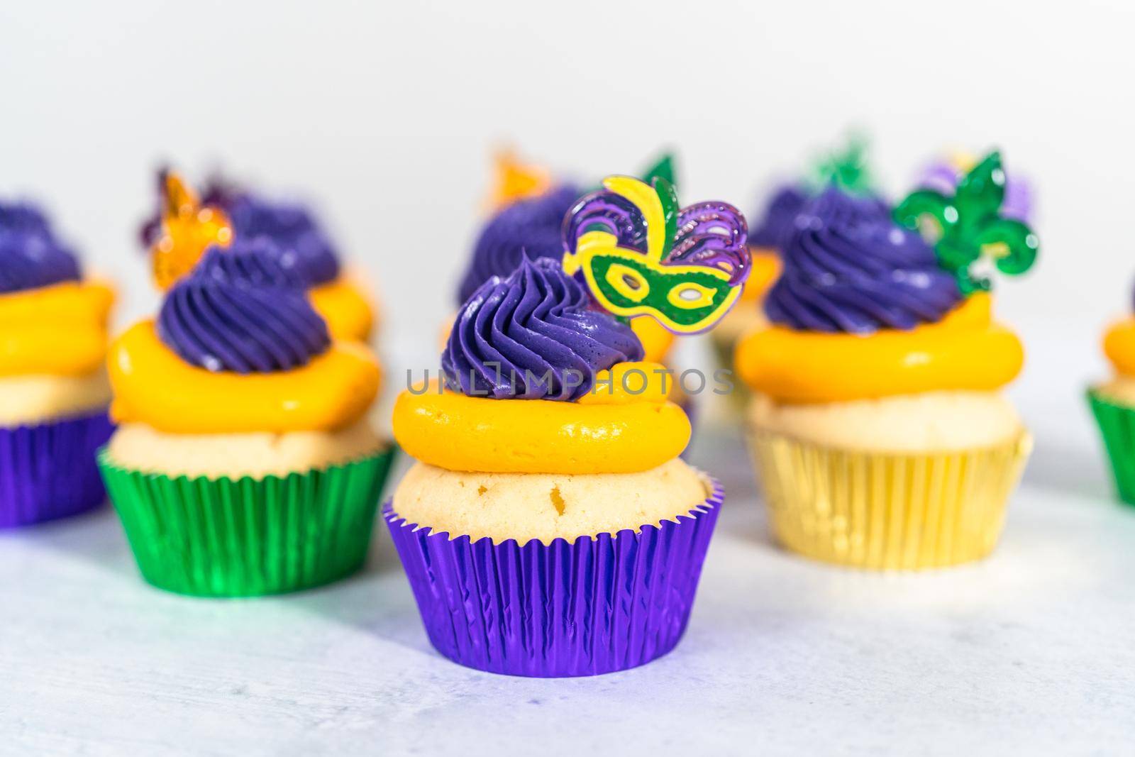 Mardi Gras vanilla cupcakes in foil cupcake cups and decorated with Italian buttercream frosting.