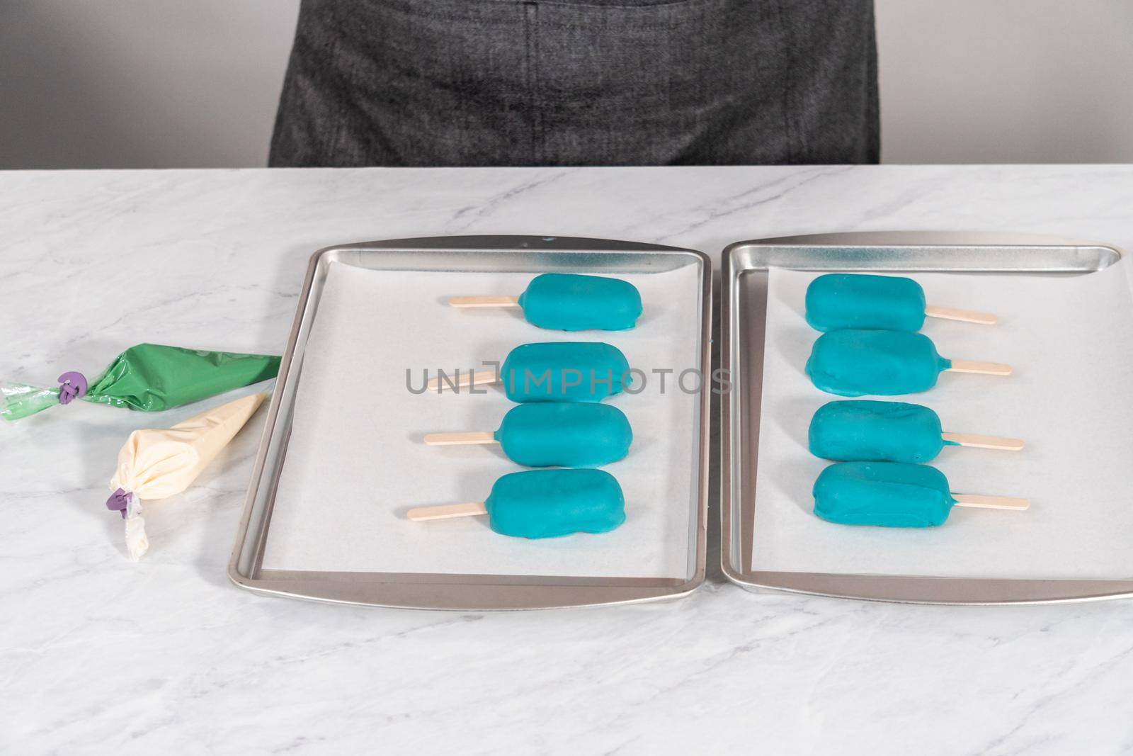 Decorating cakesicles with drizzled chocolate, chocolate mermaid tails, and seashells.
