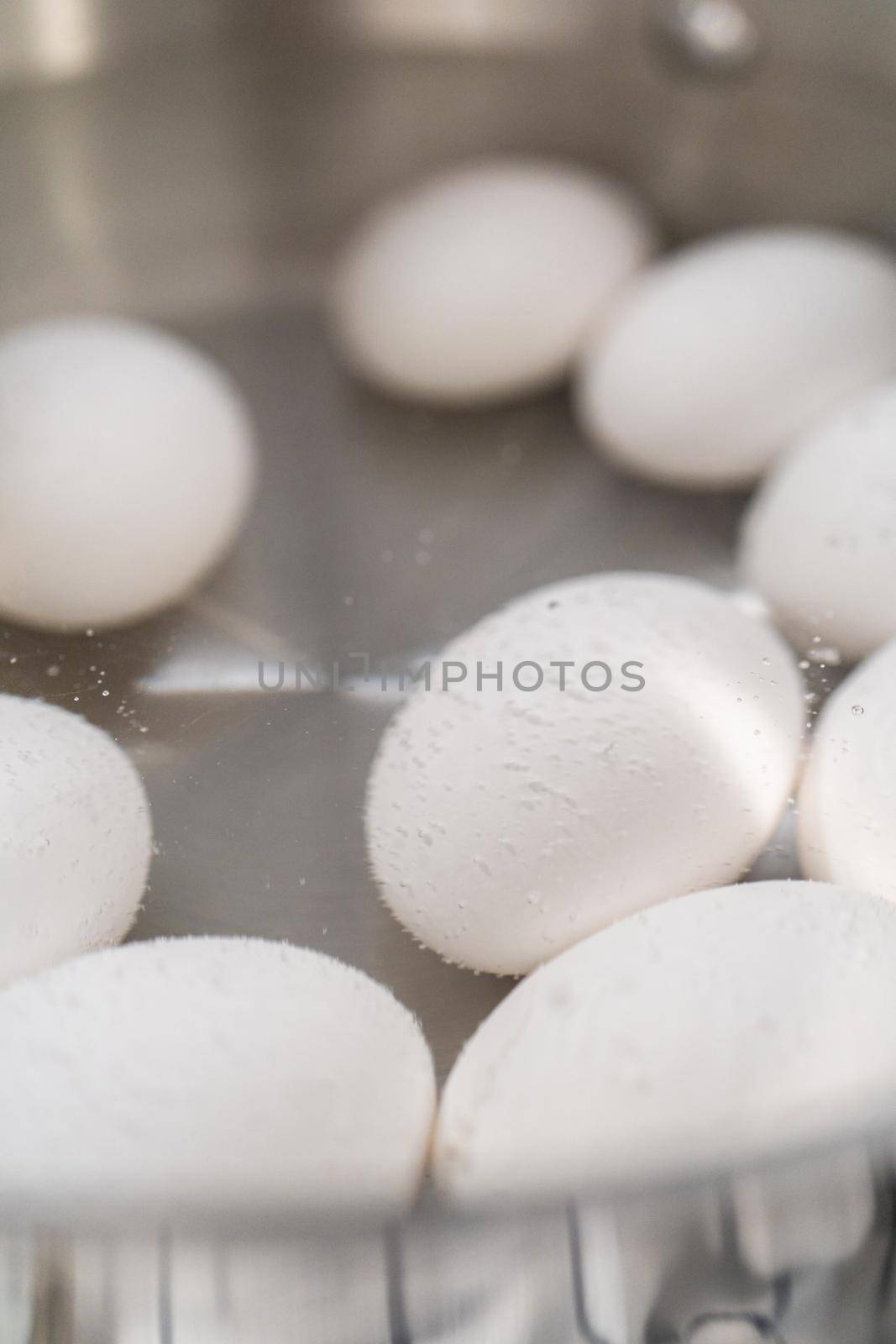 Boiling white eggs in a cooking pot to prepare hard-boiled eggs.