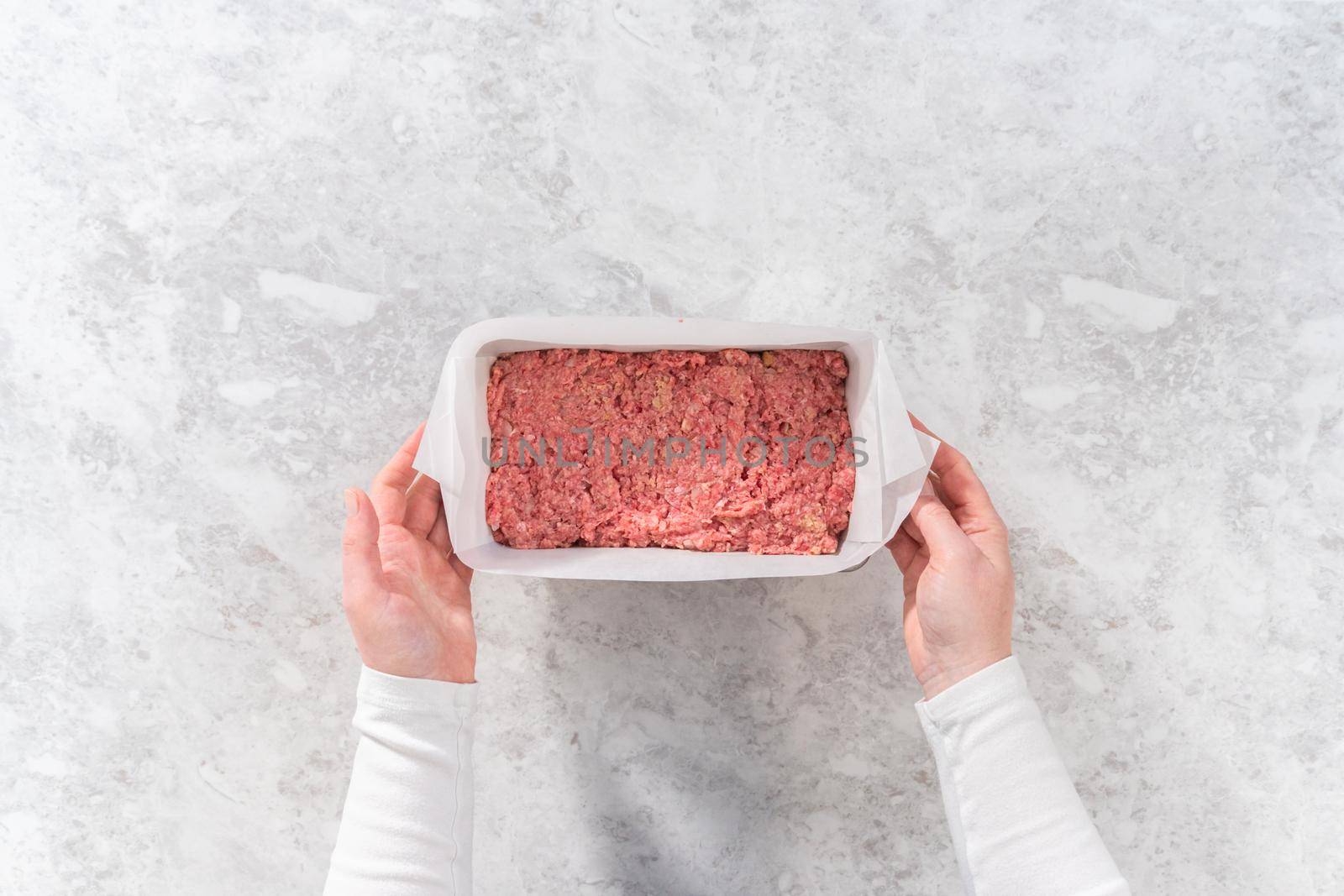 Flat lay. Preparing classic meatloaf in a loaf pan lined with parchment paper.
