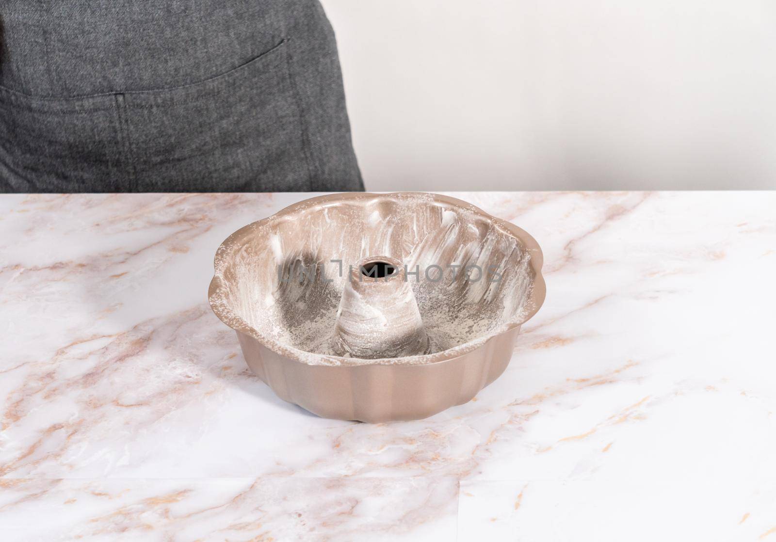 Greasing bunt cake pan to bake apple bundt cake with caramel glaze.