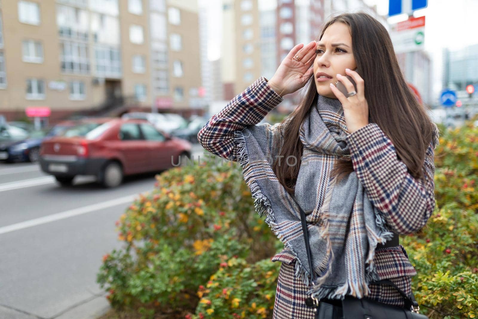 a young woman is talking on the phone and cannot find the right address in confusion Looks around.