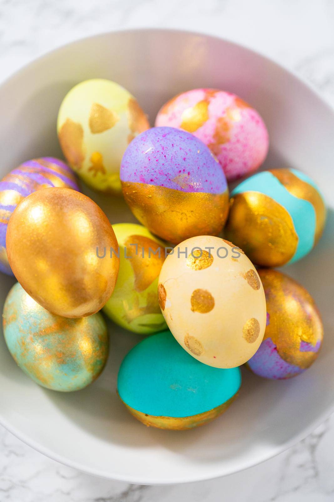 Colored and painted with gold hard-boiled eggs on a marble background.