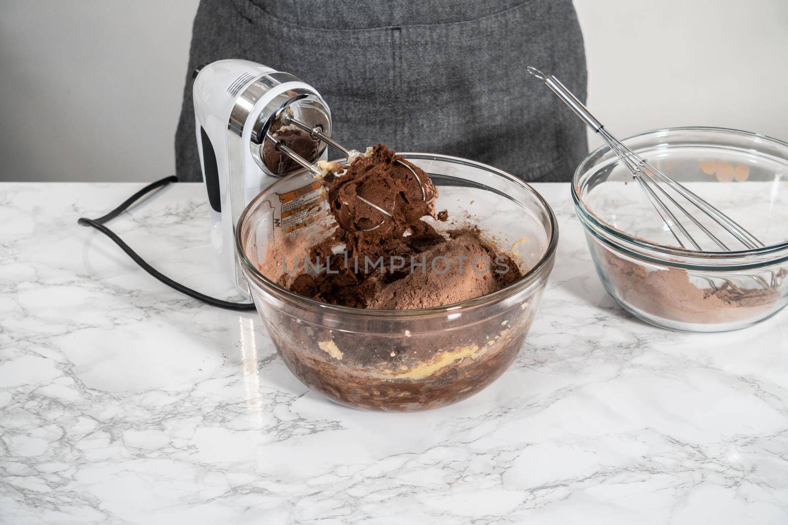Mixing ingredients in a large glass mixing bowl to bake peppermint white chocolate cookies.