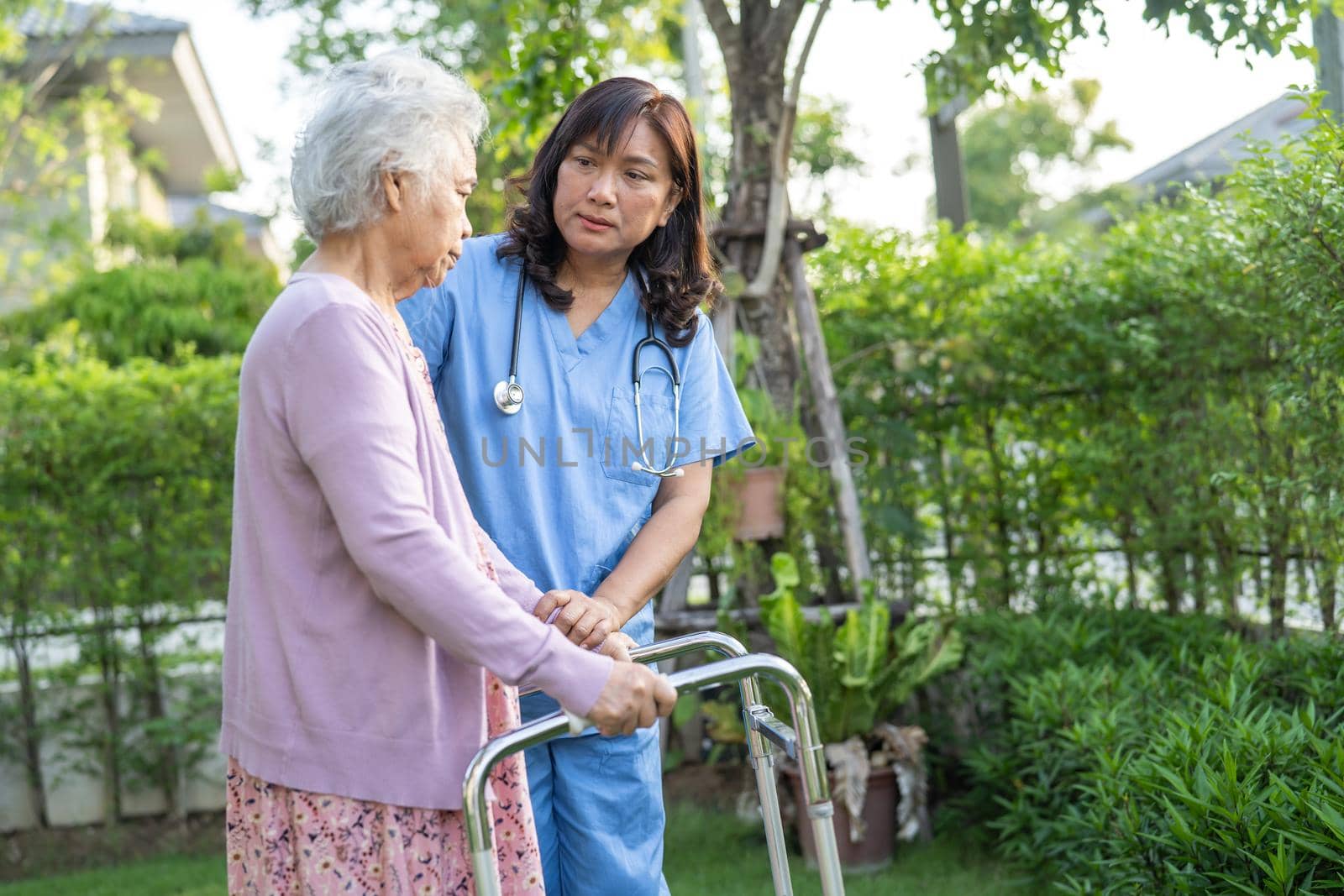 Doctor help and care Asian senior or elderly old lady woman use walker with strong health while walking at park in happy fresh holiday. by pamai