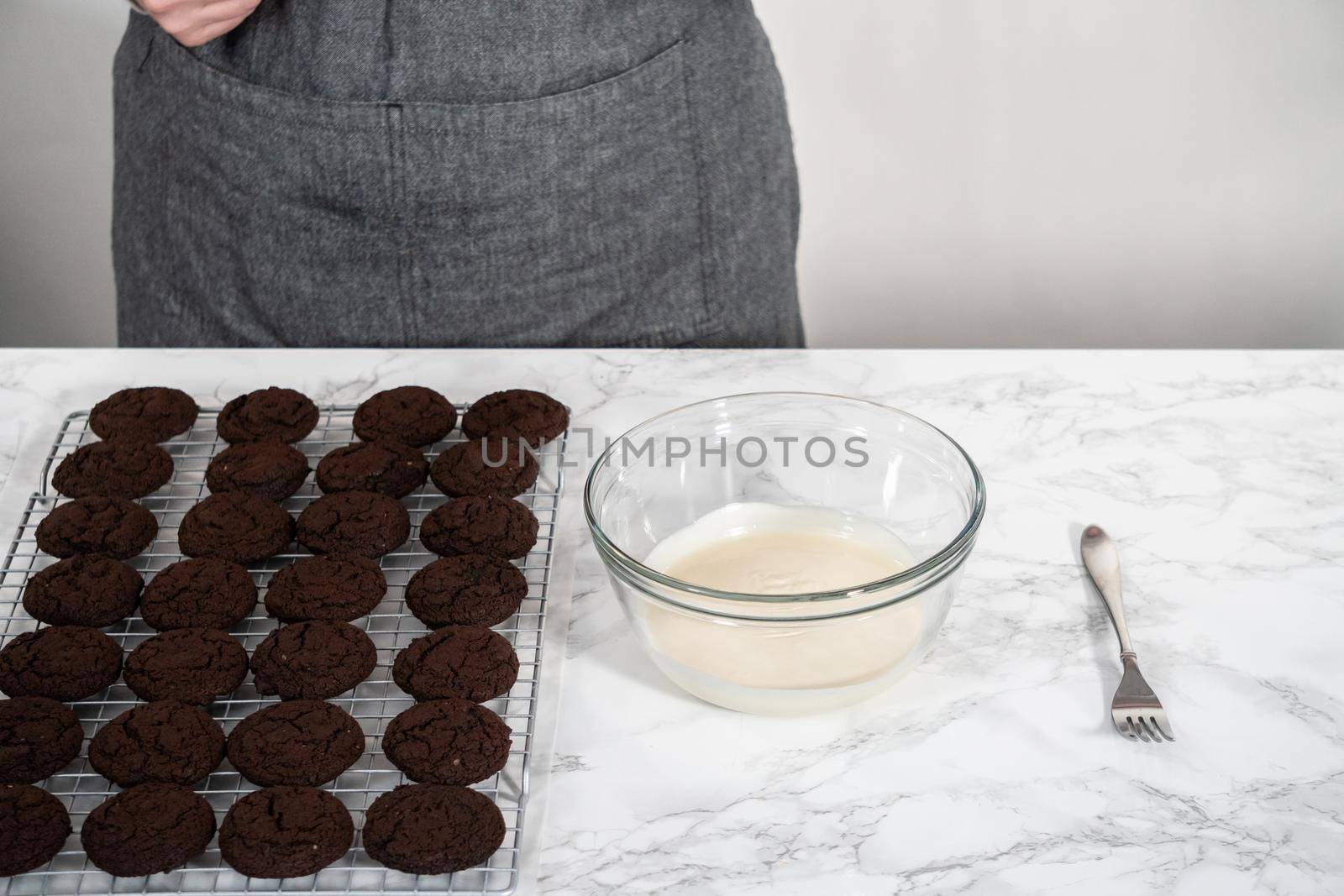 Dipping chocolate cookies into the melted white chocolate to prepare peppermint white chocolate cookies.