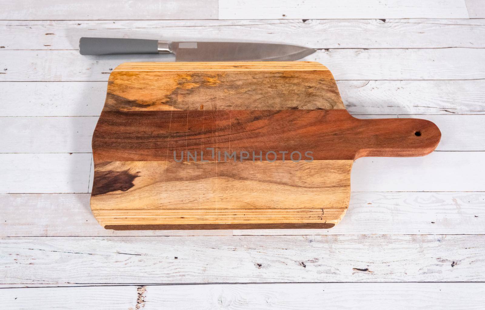 Empty rustic wooden cutting board with kitchen knife.