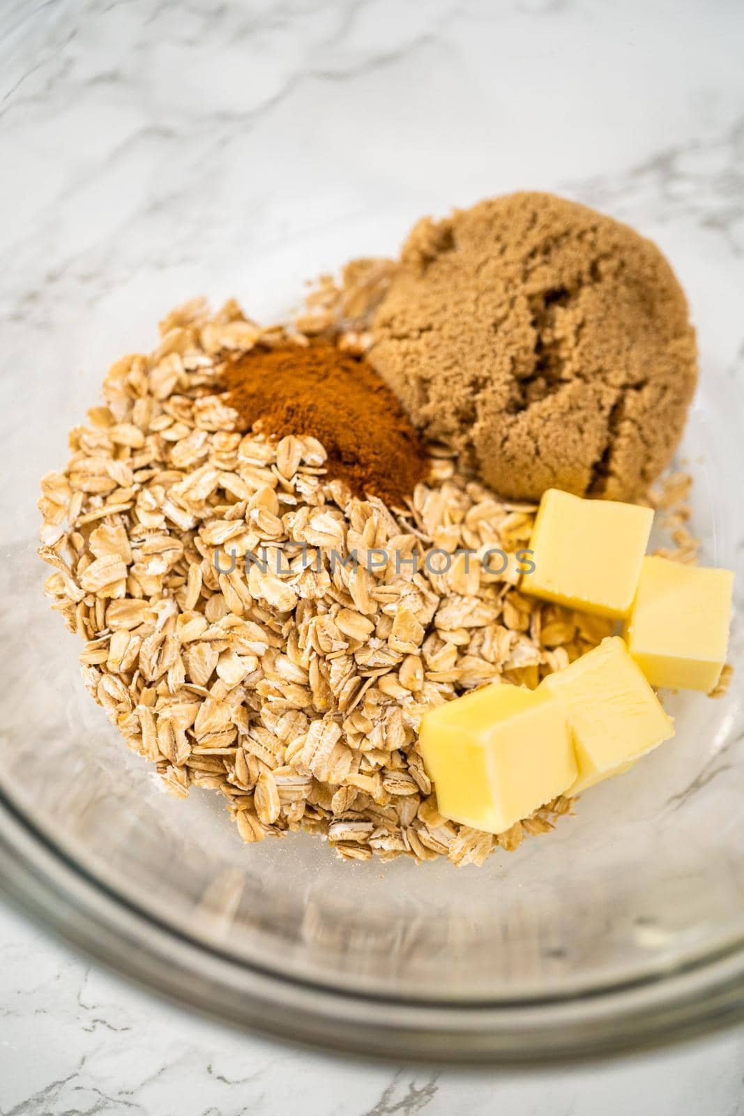 Mixing ingredients in a large glass mixing bowl to bake banana oatmeal muffins.