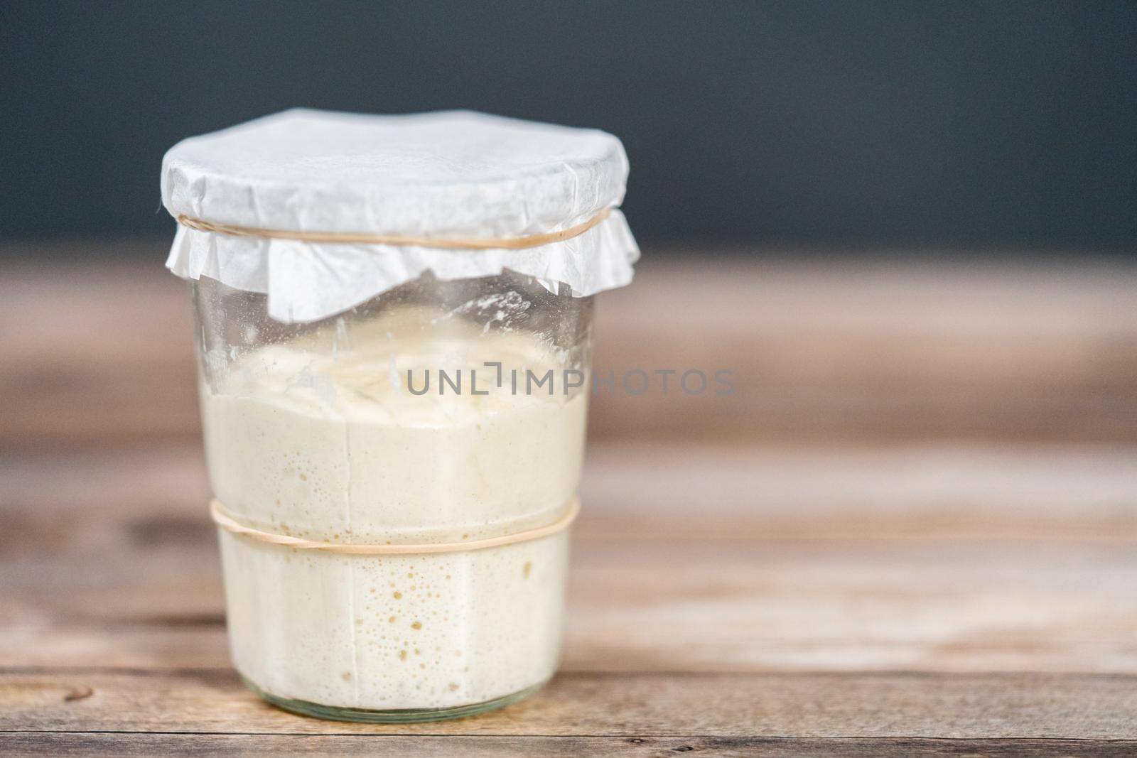 Feeding sourdough starter in a glass mason jar for baking artisan bread.